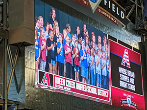 Jumbotron image of Queen Creek choir singing the national anthem at a Diamondbacks baseball game.