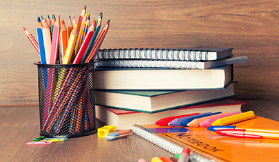 Colored pencils and books on a wood desk