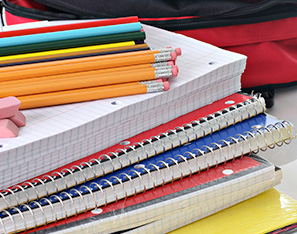 pencils, erasers and notebooks next to a backpack